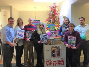 A group of Johnson Duffie attorneys holding toys in front of a box that says toys for tots
