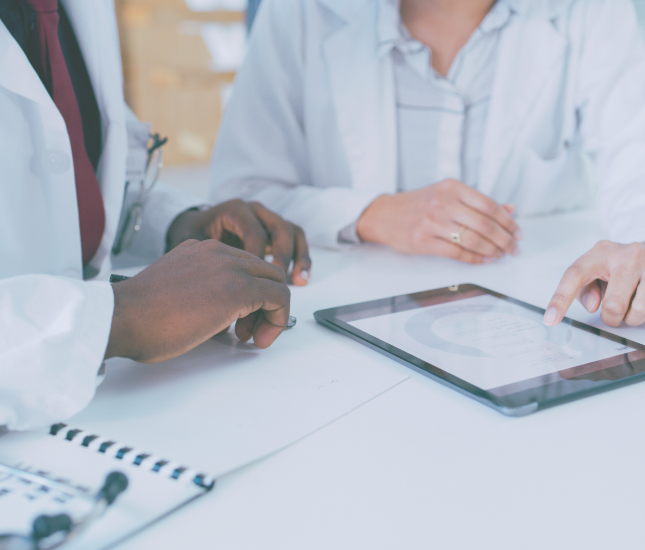 Two doctors are looking at a tablet with a graph on it