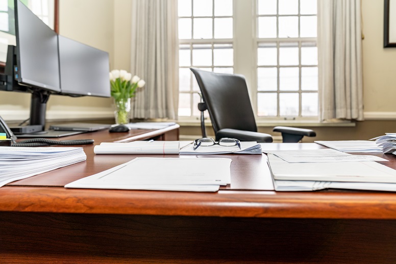 office desk with dual monitors and papers on it