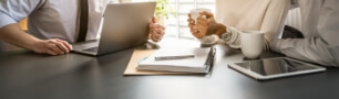 Two people are sitting at a table with a laptop and a tablet .
