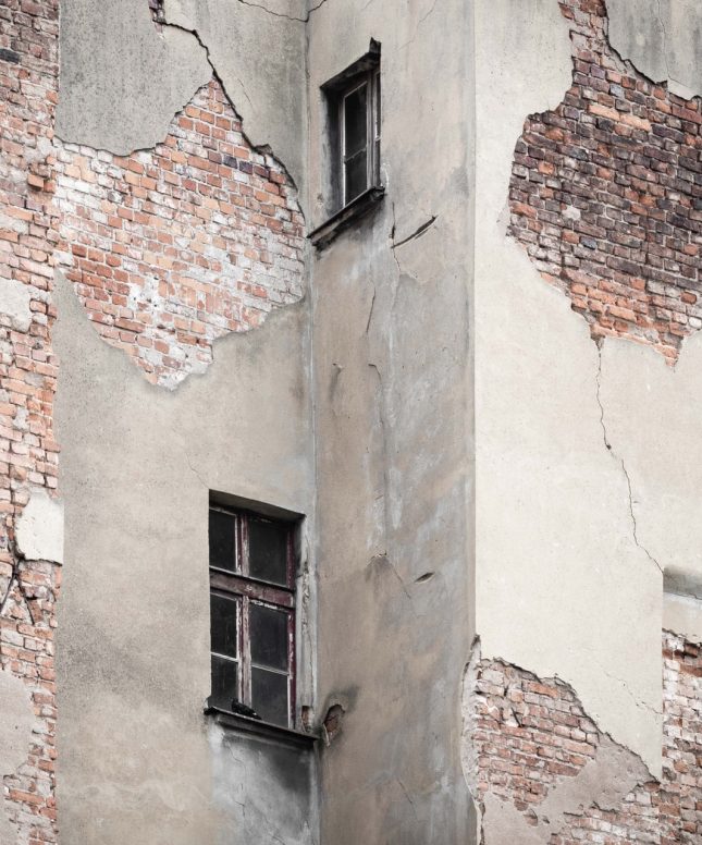 A brick building with a cracked wall and a window