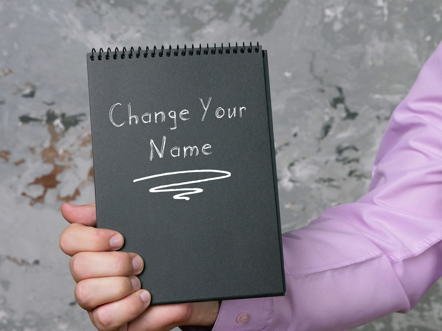 Man holding a notebook that says change your name on the front