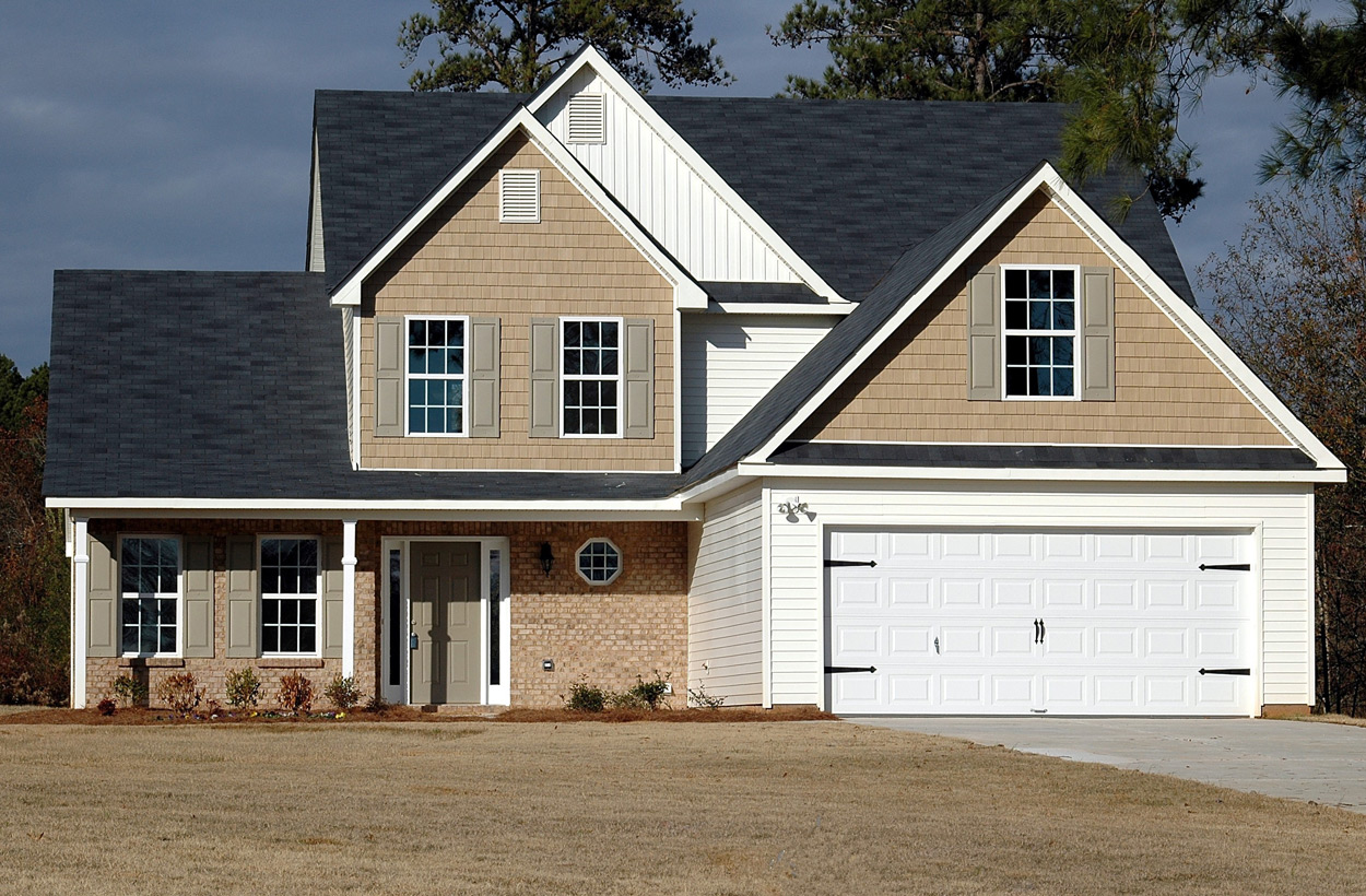 A brown house with an attached garage and yard in the front