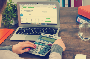 women with a calculator and laptop in front of her working on a tax spreadsheet