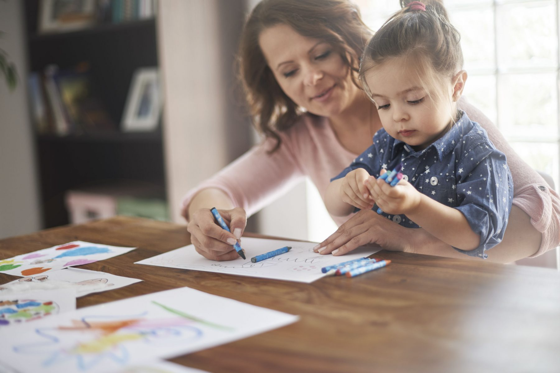 parent holding their toddler and coloring with them