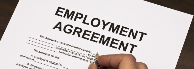 A person is signing an employment agreement with a pen