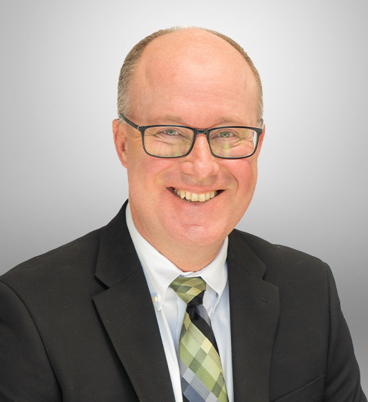 Mark Duffie headshot in a black suit jacket and tie.