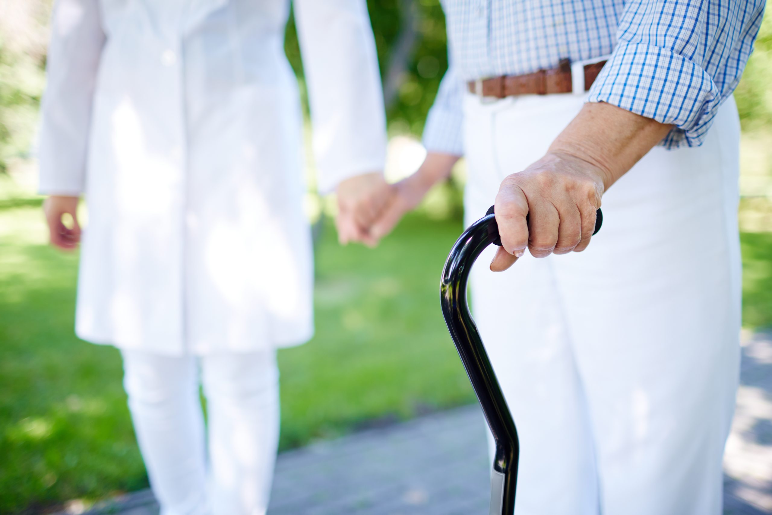 A man holding a cane while holding a woman 's hand